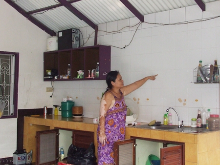 Pa Thongmuan points out how high she said the flood waters reached inside her home.